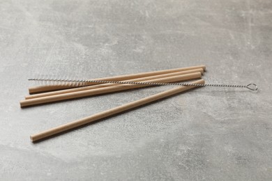 Photo of Bamboo drinking straws and cleaning brush on gray textured table