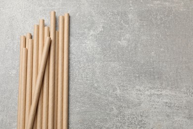 Photo of Bamboo drinking straws on gray textured table, top view. Space for text