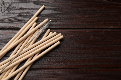 Photo of Bamboo drinking straws on wooden table, top view. Space for text