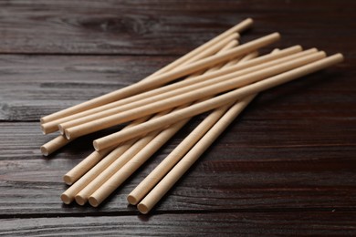 Photo of Bamboo drinking straws on wooden table, closeup