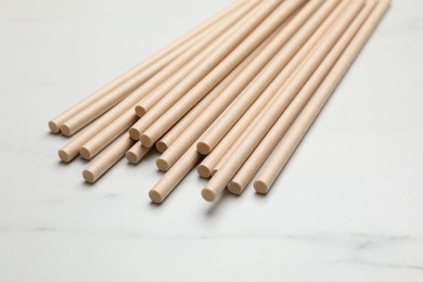 Photo of Bamboo drinking straws on light marble table, closeup