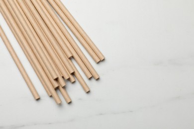 Photo of Bamboo drinking straws on light marble table, top view. Space for text