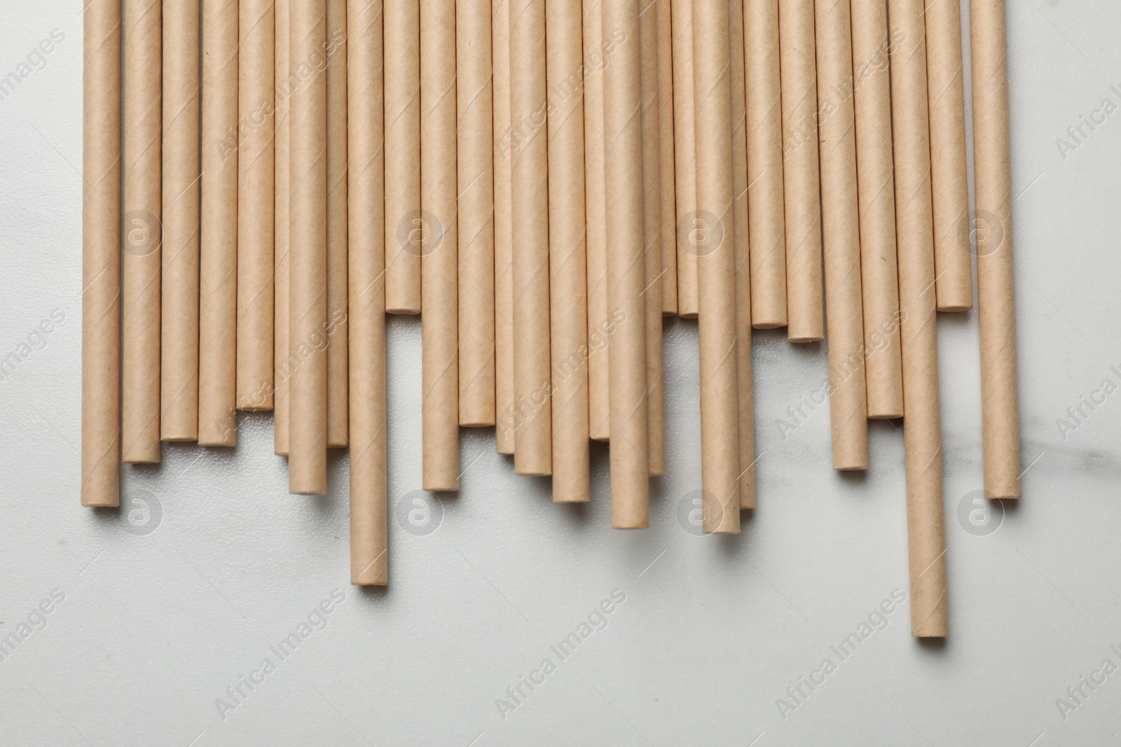 Photo of Bamboo drinking straws on light marble table, top view