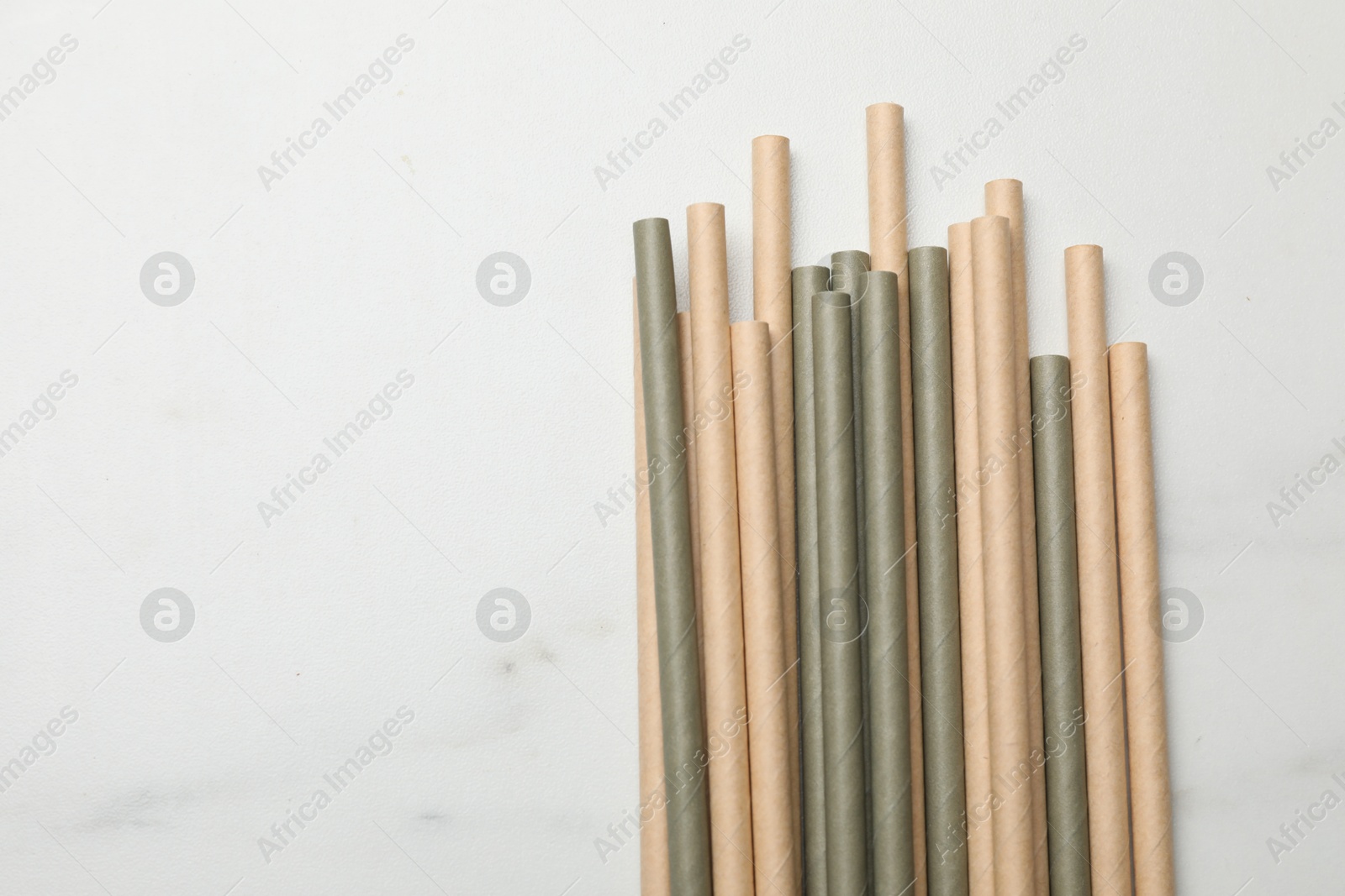 Photo of Bamboo drinking straws on light marble table, top view. Space for text