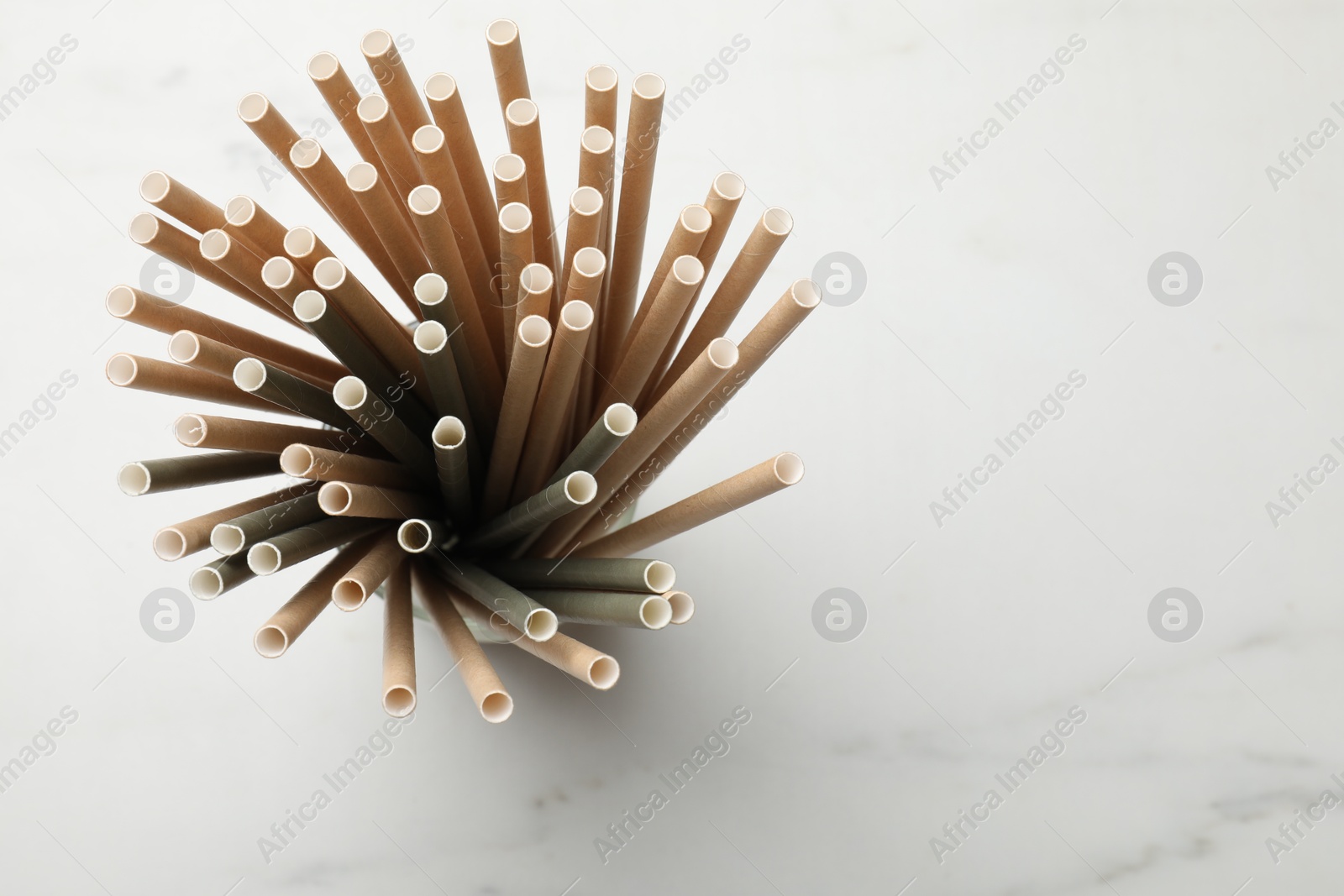 Photo of Bamboo drinking straws on light marble table, top view. Space for text