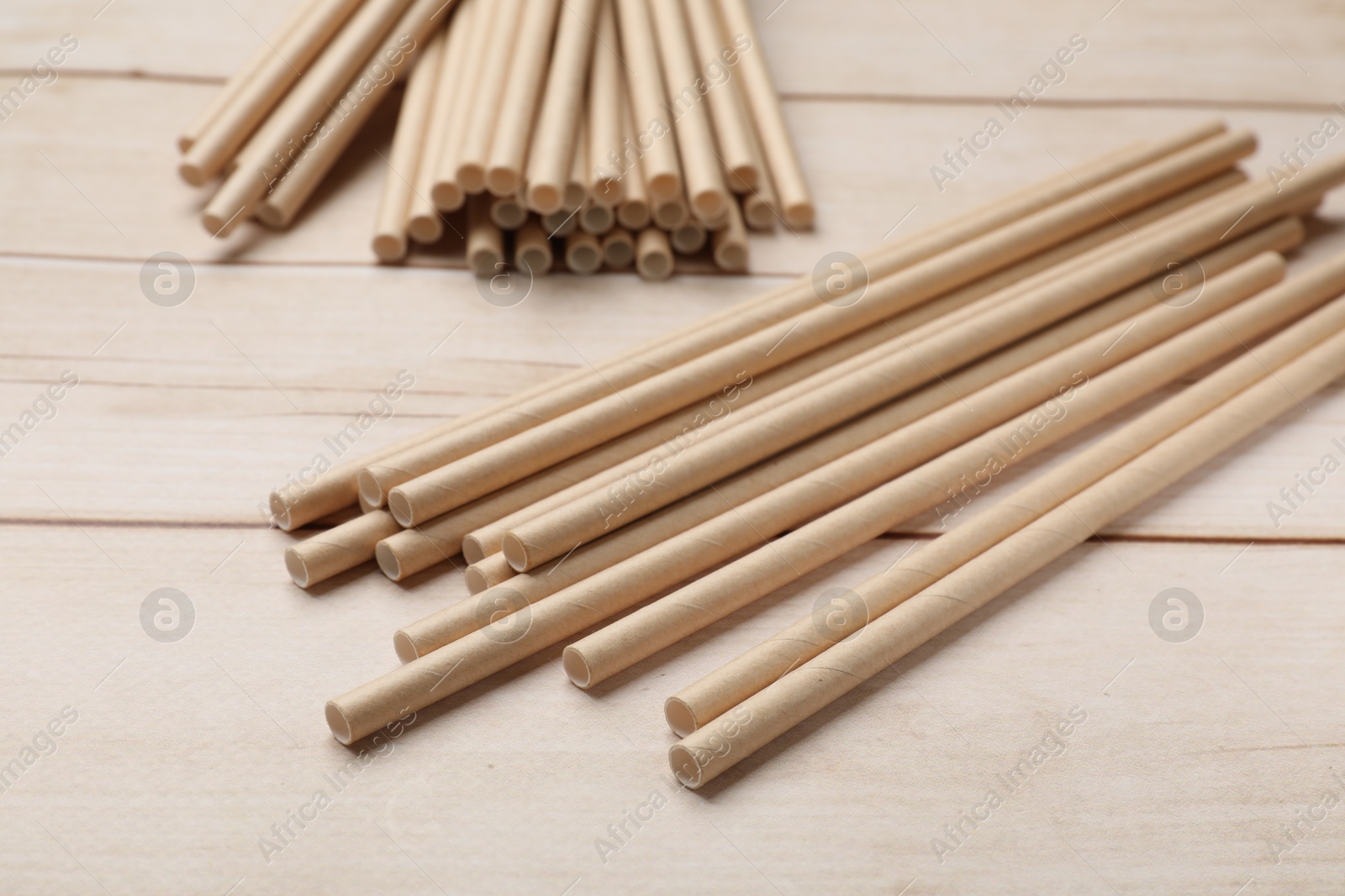 Photo of Bamboo drinking straws on wooden table, closeup