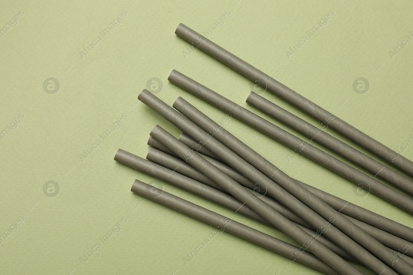 Photo of Bamboo drinking straws on green background, top view. Space for text