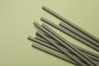 Photo of Bamboo drinking straws on green background, top view. Space for text