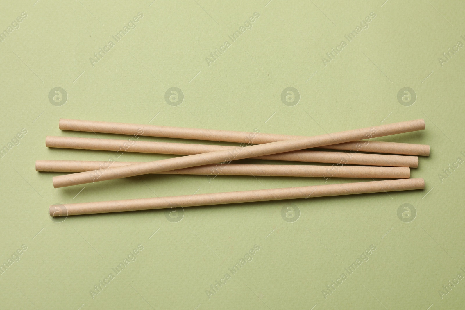 Photo of Bamboo drinking straws on green background, top view