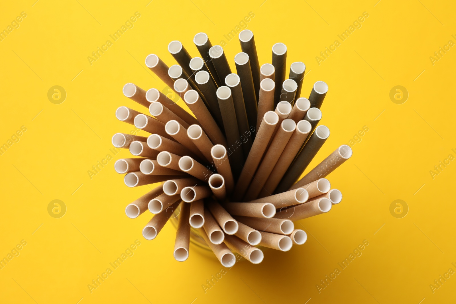 Photo of Bamboo drinking straws on yellow background, top view