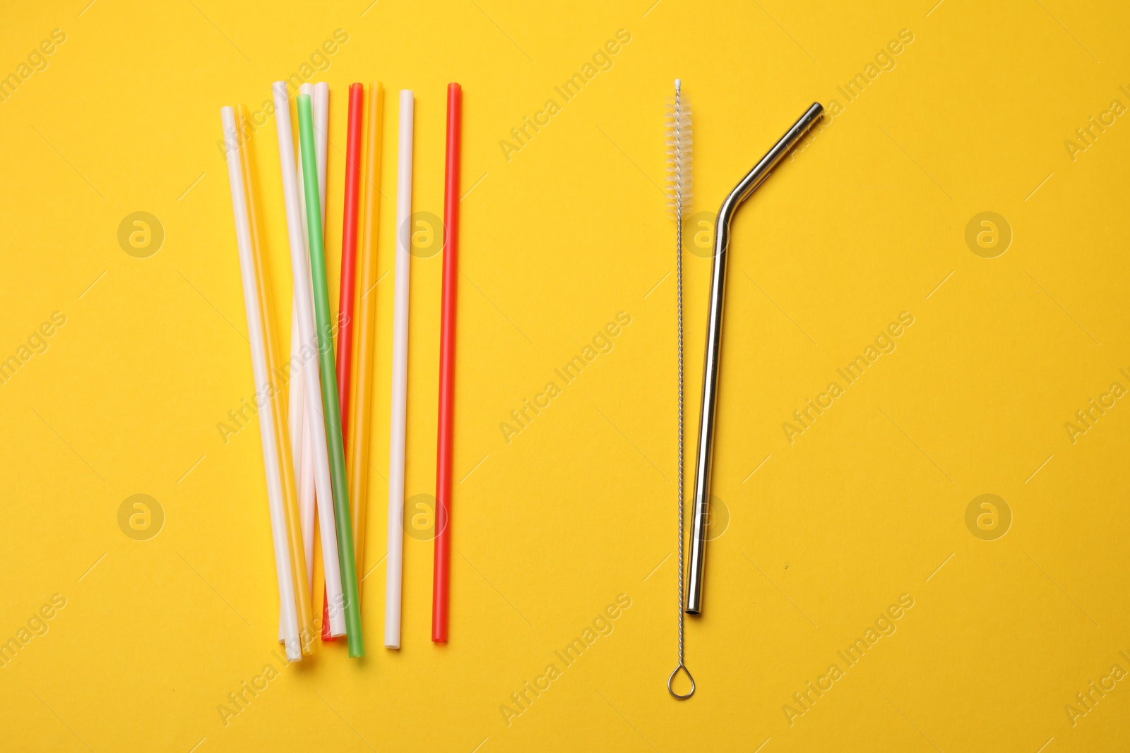 Photo of Different drinking straws and cleaning brush on yellow background, flat lay