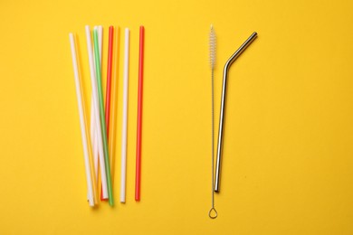 Photo of Different drinking straws and cleaning brush on yellow background, flat lay