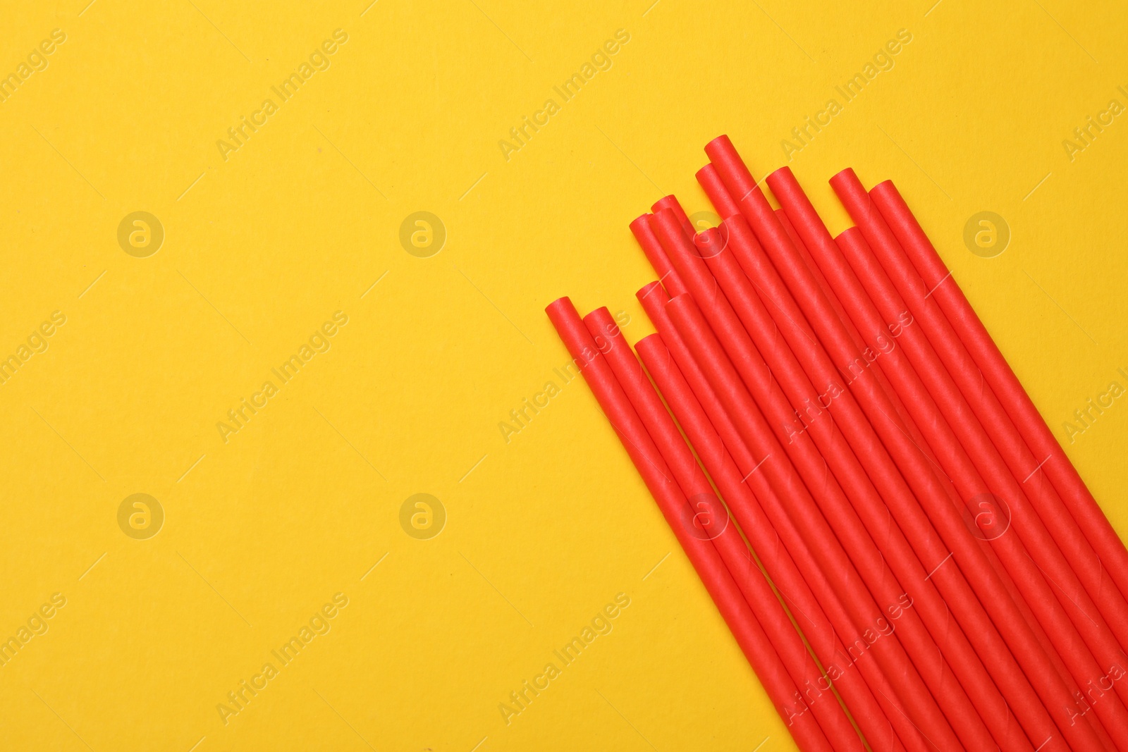 Photo of Bamboo drinking straws on yellow background, top view. Space for text