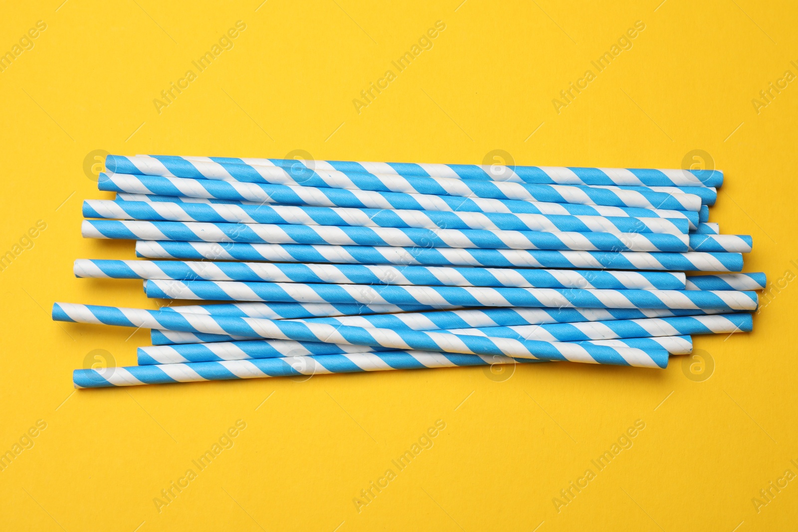 Photo of Paper drinking straws on yellow background, top view