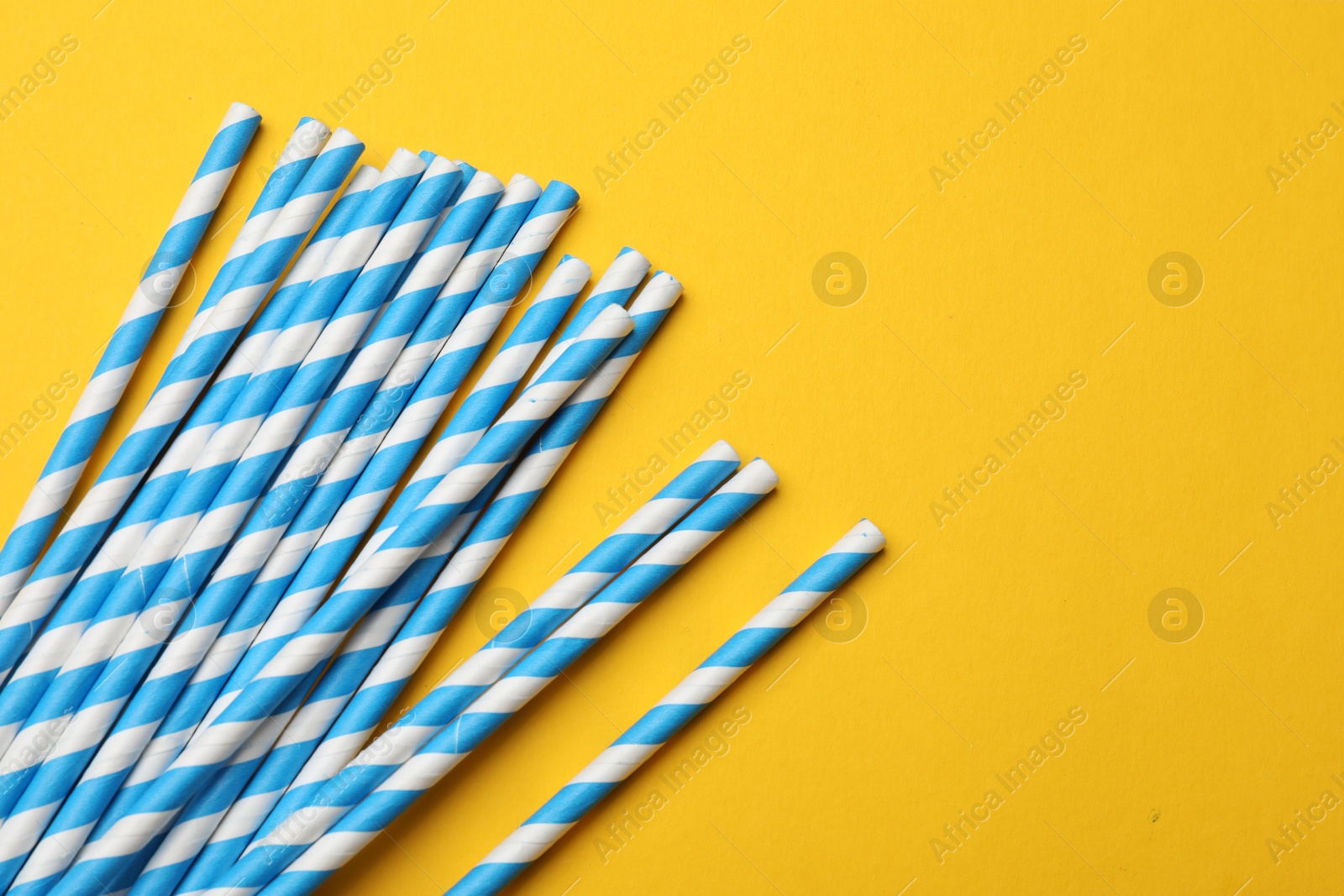 Photo of Paper drinking straws on yellow background, top view. Space for text