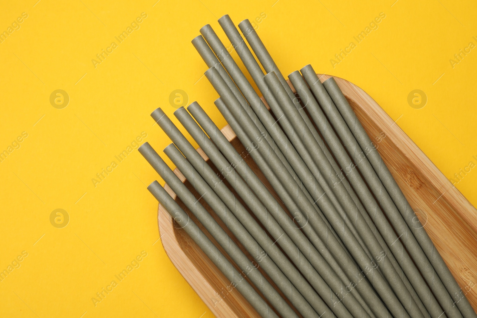 Photo of Bamboo drinking straws on yellow background, top view