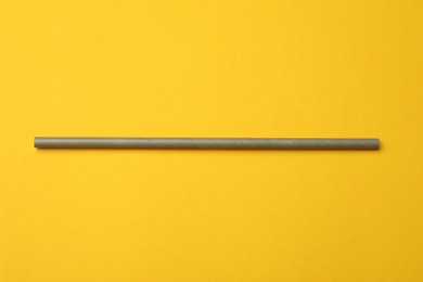 Photo of Bamboo drinking straw on yellow background, top view