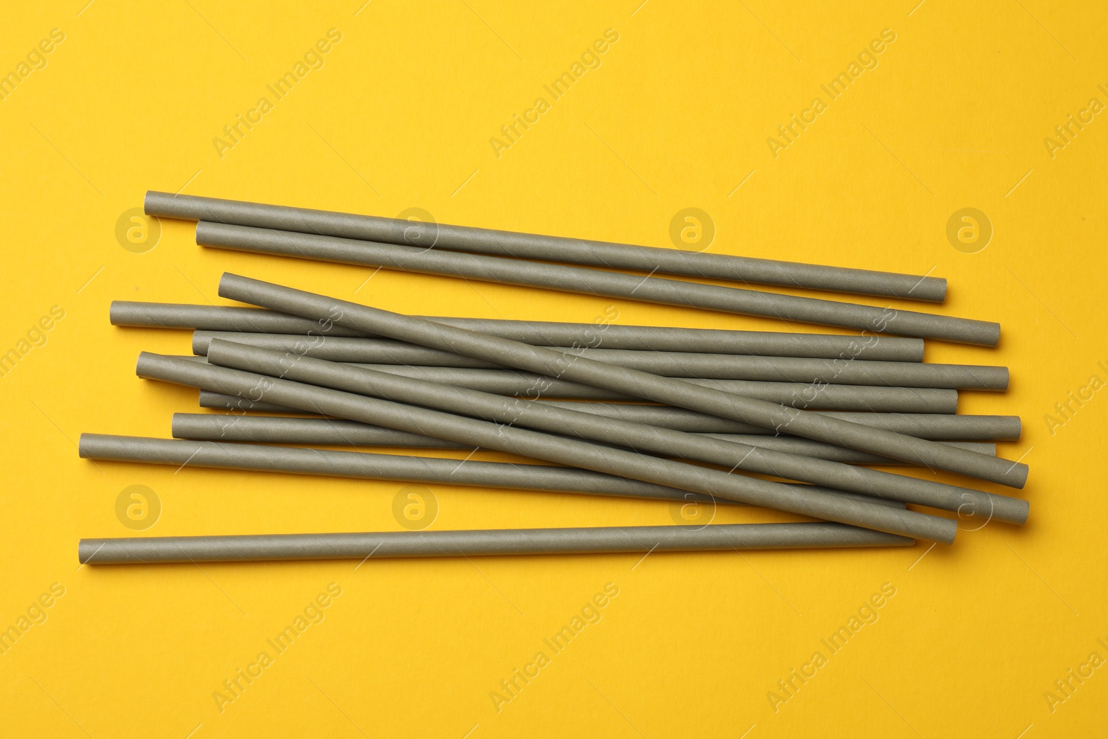 Photo of Bamboo drinking straws on yellow background, top view