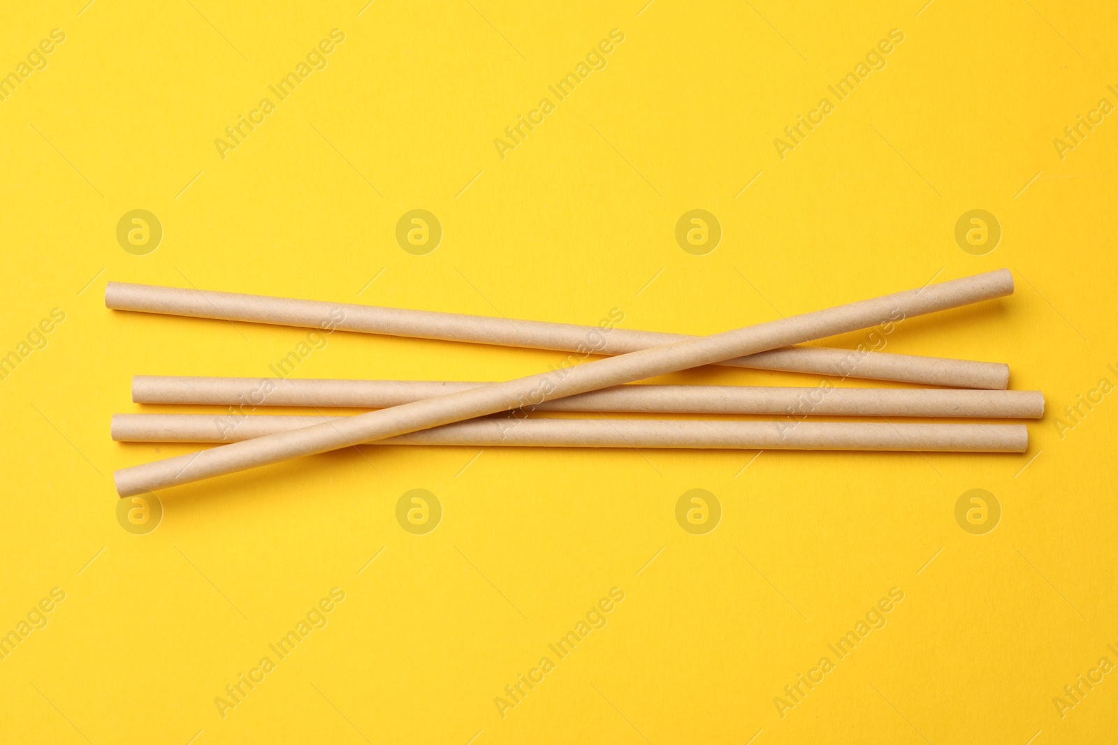 Photo of Bamboo drinking straws on yellow background, top view