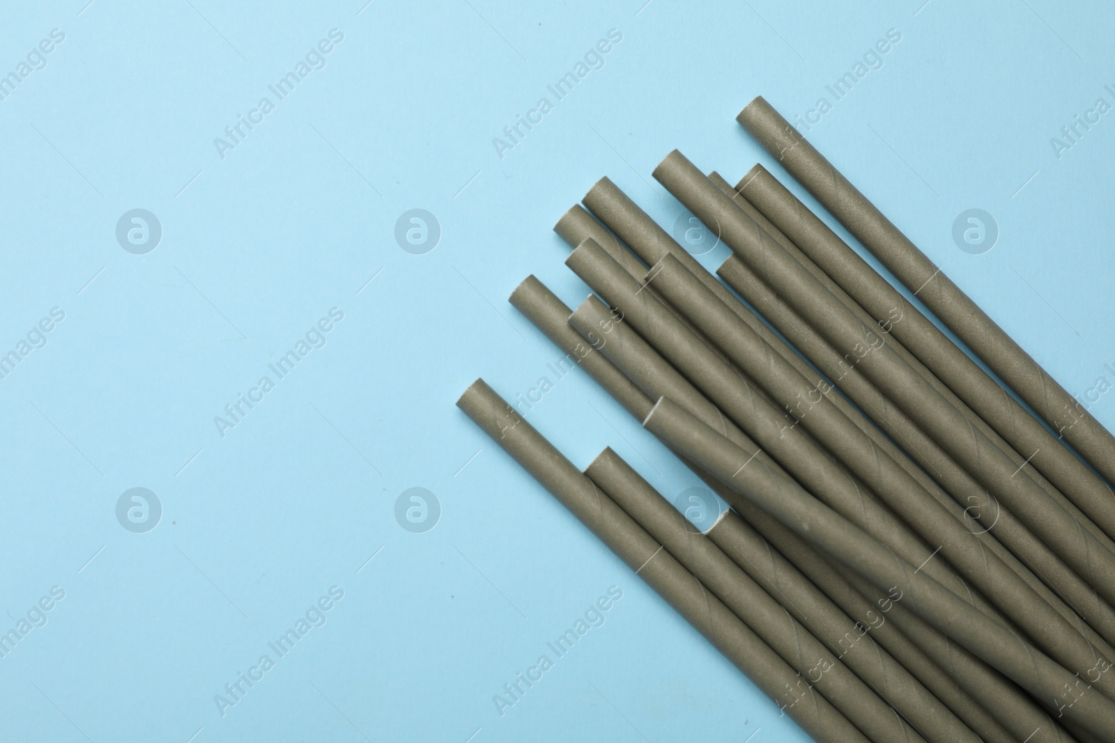 Photo of Bamboo drinking straws on light blue background, top view. Space for text