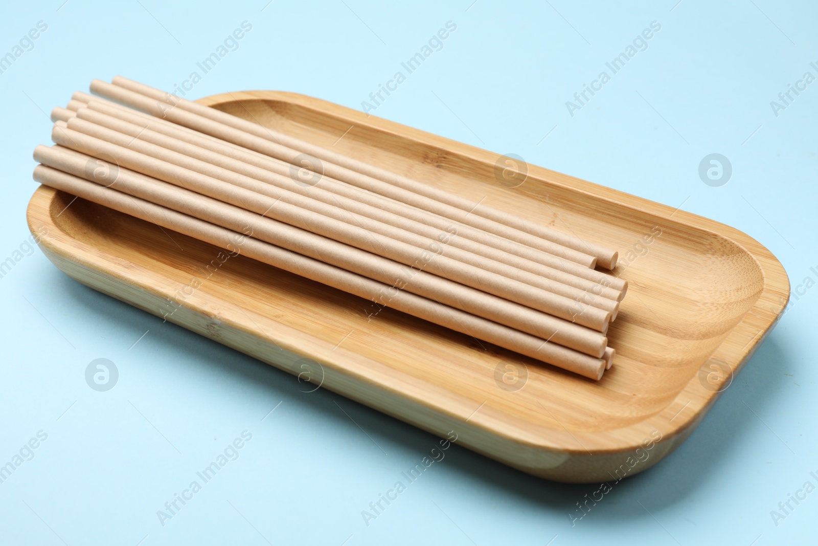 Photo of Bamboo drinking straws on light blue background, closeup