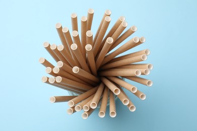 Photo of Bamboo drinking straws on light blue background, top view