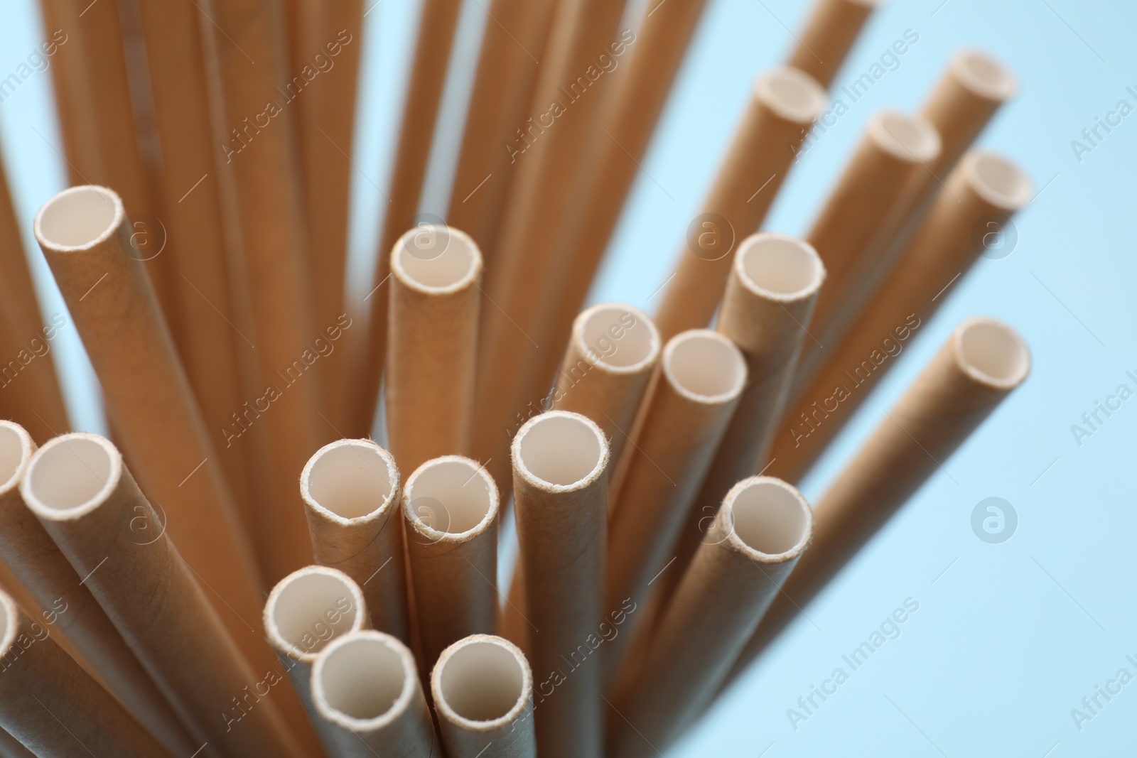 Photo of Bamboo drinking straws on light blue background, closeup