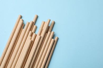 Photo of Bamboo drinking straws on light blue background, top view. Space for text