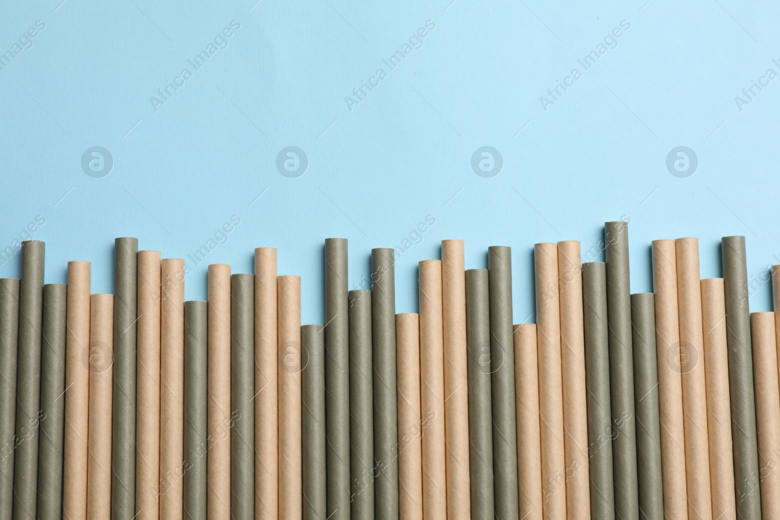 Photo of Bamboo drinking straws on light blue background, top view. Space for text