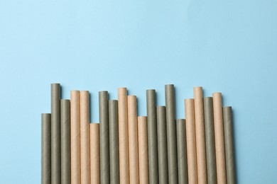 Photo of Bamboo drinking straws on light blue background, top view. Space for text