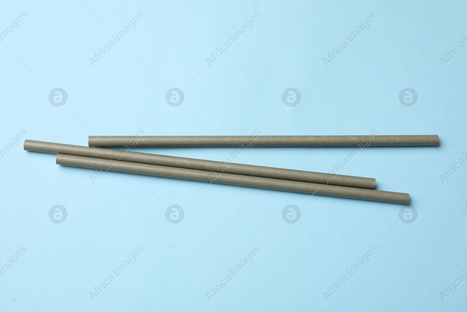 Photo of Bamboo drinking straws on light blue background, top view