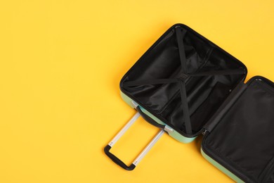 Photo of Open empty suitcase on yellow background, above view. Space for text