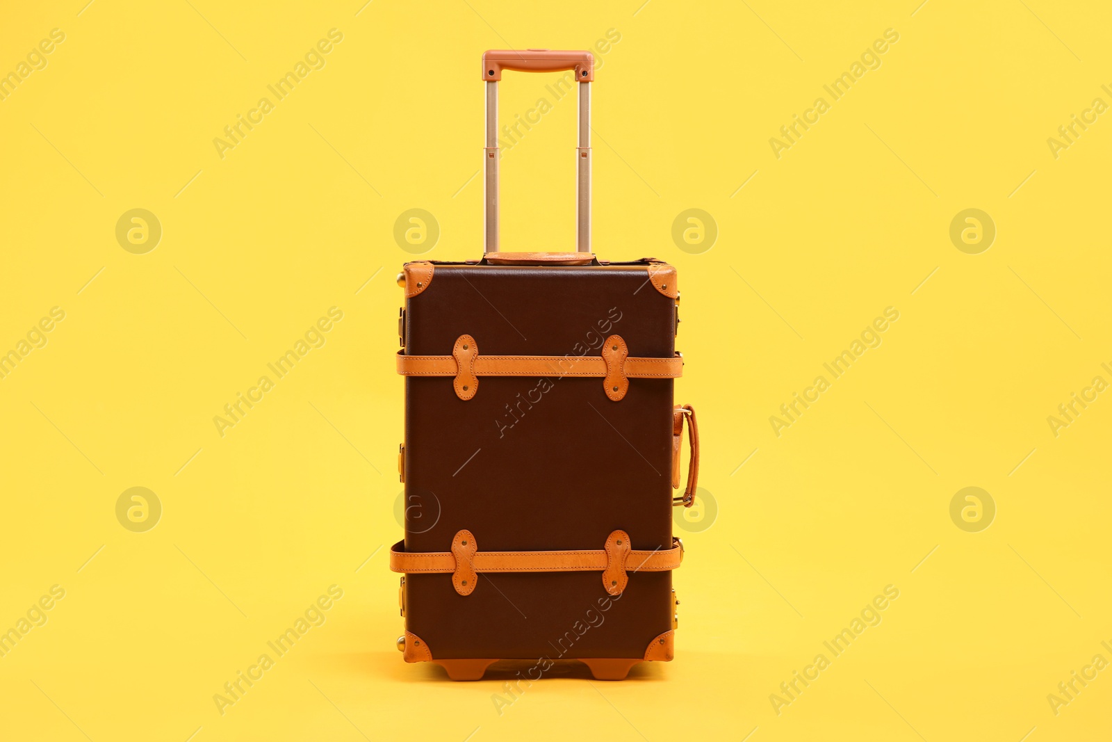 Photo of One new brown suitcase on yellow background