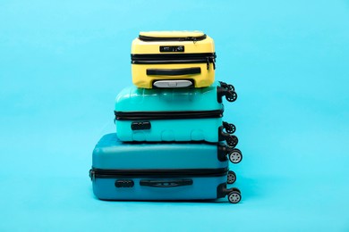 Stack of different suitcases on light blue background