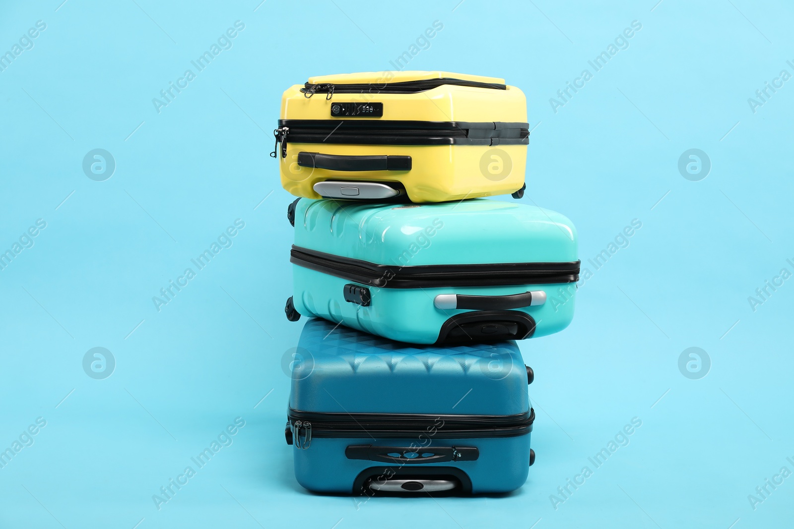 Photo of Stack of different suitcases on light blue background