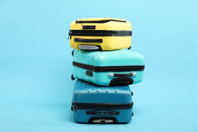 Photo of Stack of different suitcases on light blue background