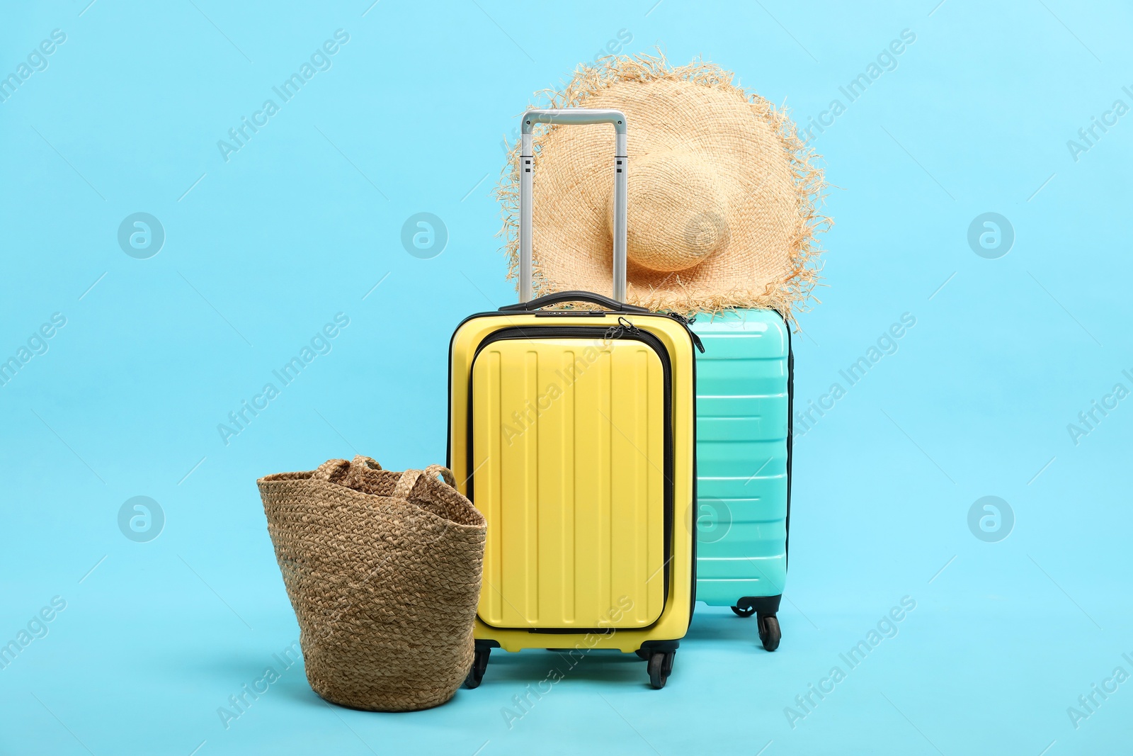 Photo of Suitcases with straw hat and bag on light blue background