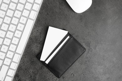 Photo of Leather card holder with blank business cards, mouse and keyboard on grey textured table, flat lay