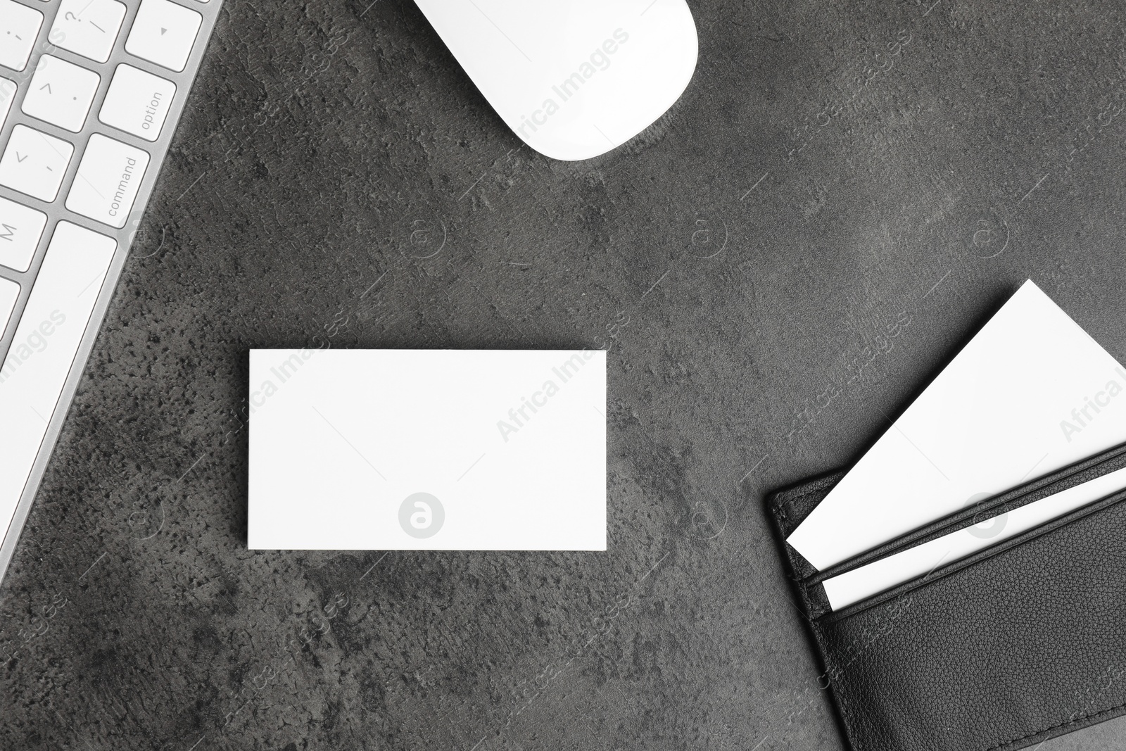 Photo of Leather card holder with blank business cards, mouse and keyboard on grey textured table, flat lay. Mockup for design