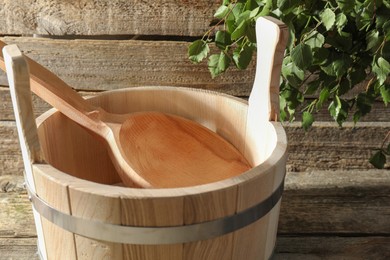 Photo of Sauna equipment. Bucket and ladle on wooden surface, closeup