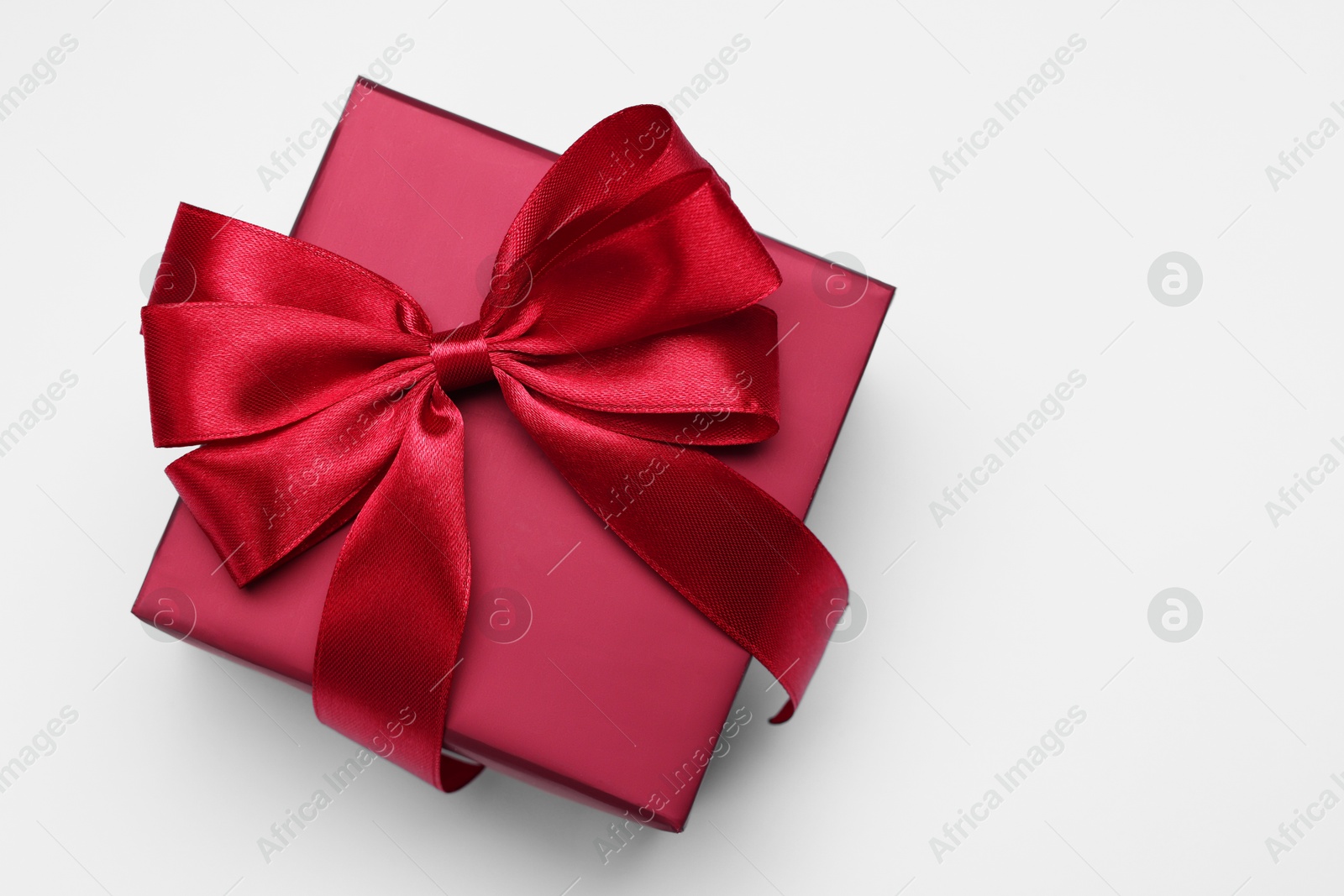 Photo of Gift box with bow on light grey background, top view. Space for text