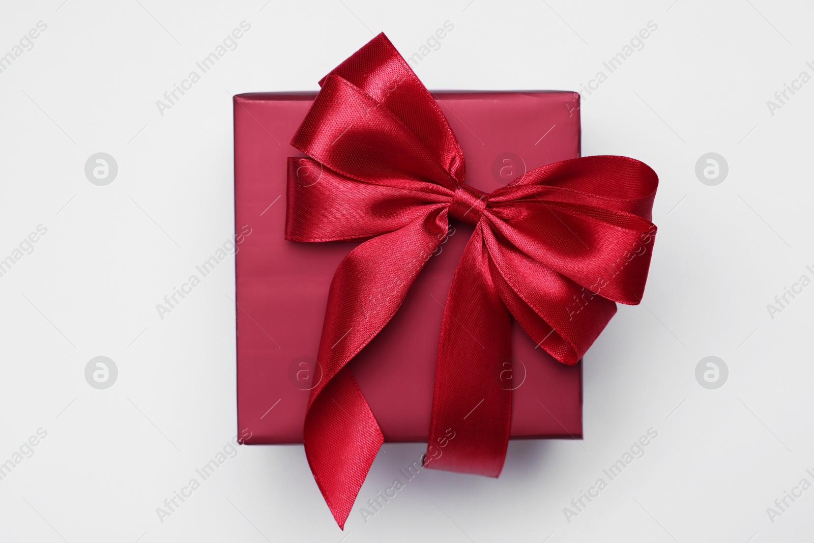 Photo of Gift box with bow on light grey background, top view