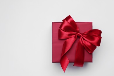 Photo of Gift box with bow on light grey background, top view. Space for text