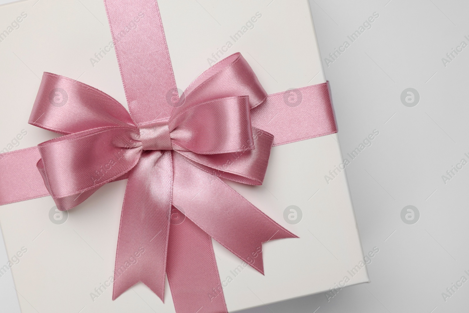 Photo of Gift box with pink bow on light grey background, top view