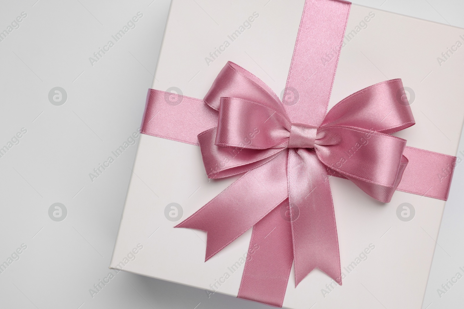 Photo of Gift box with pink bow on light grey background, top view