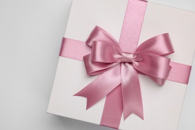 Photo of Gift box with pink bow on light grey background, top view