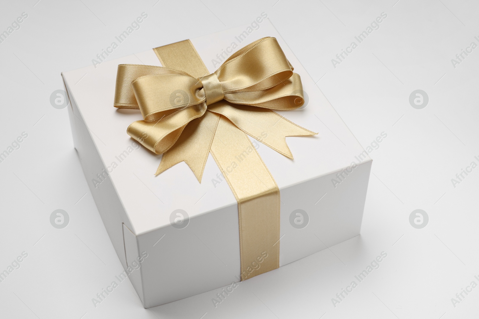 Photo of Gift box with golden bow on light grey background