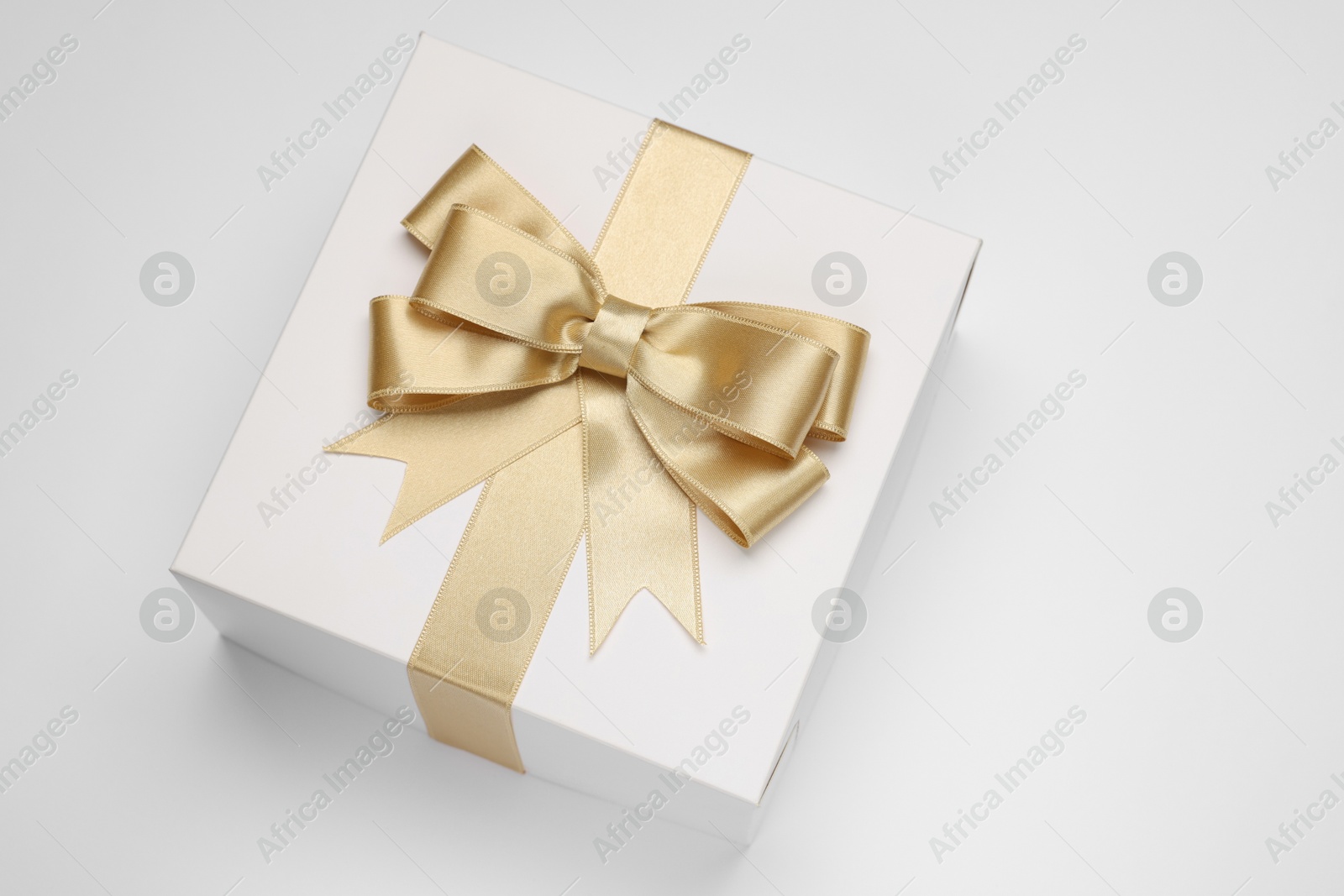 Photo of Gift box with golden bow on light grey background, above view