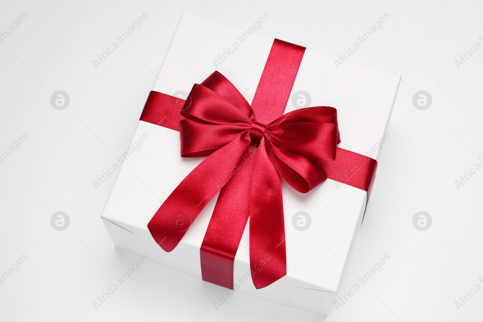 Photo of Gift box with red bow on light grey background, above view