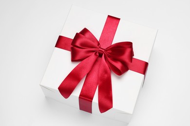 Photo of Gift box with red bow on light grey background, above view